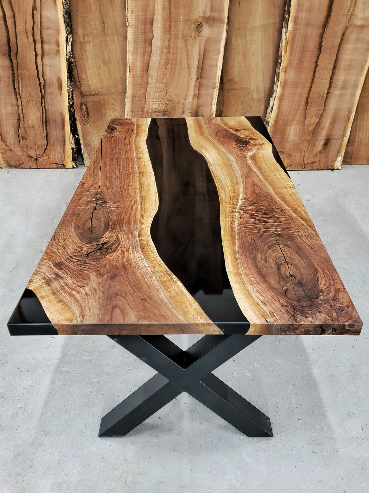 Wooden table with natural grain and black metal base on a gray surface