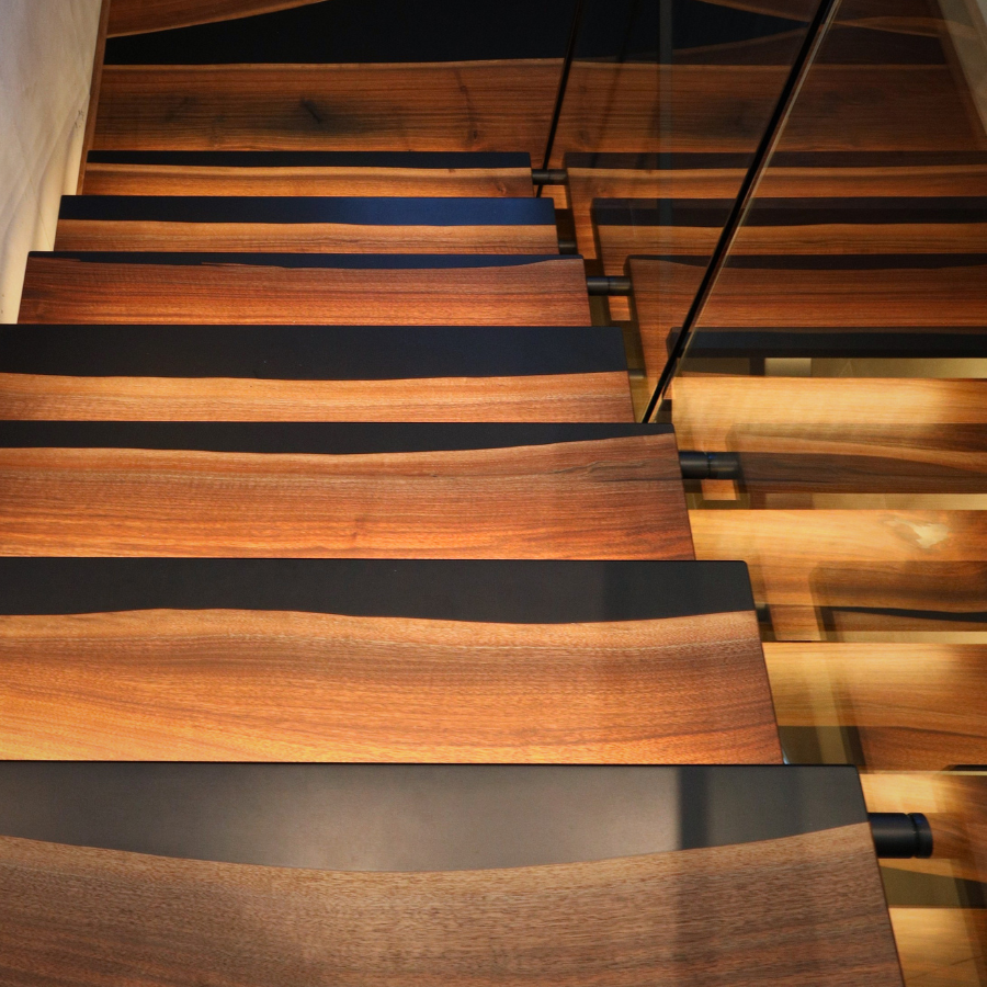 Wooden walnut staircase with black epoxy striping in a modern interior setting