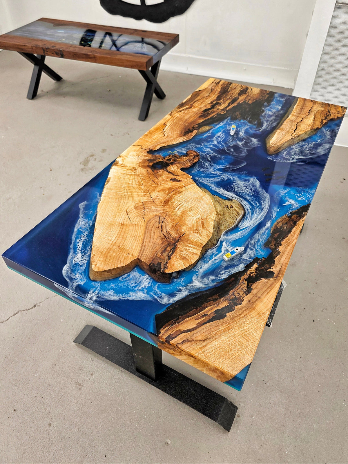 Custom wood and epoxy desk with sit-stand mechanism. Wood is maple with tons of character and spalted; epoxy is inspired by the ocean with dark and light blue sections, crashing white waves, and memorabilia inclusions (toy-sized boats)