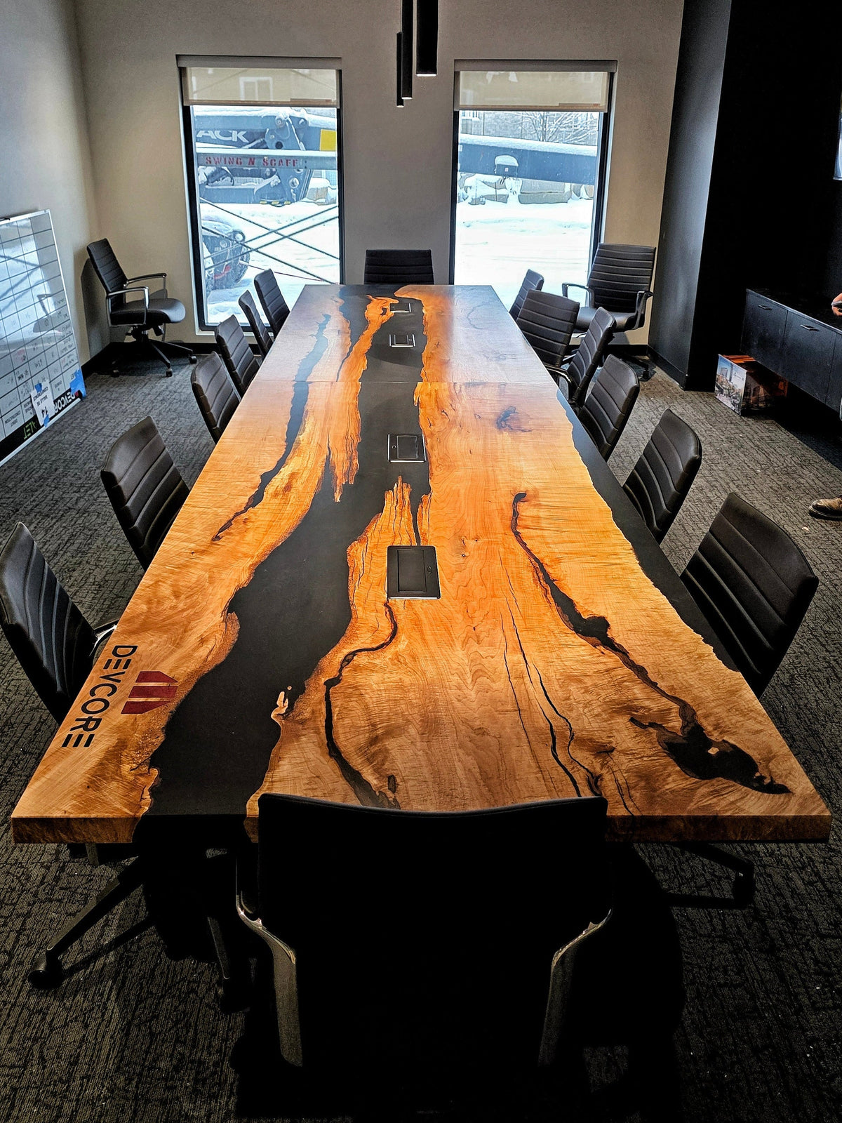 Modern conference room table made with maple and epoxy, custom engraved and epoxy-filled Devcore company logo, wireless charging throughout.