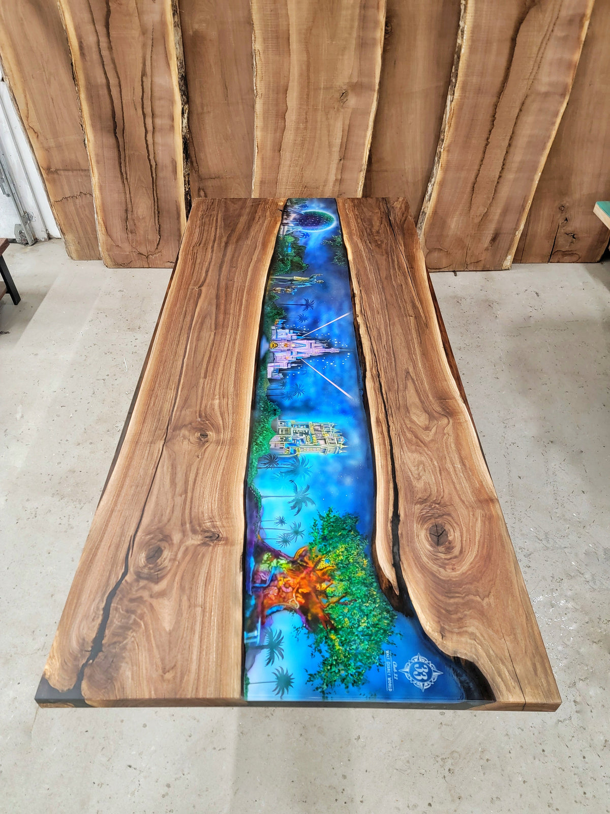 Custom wooden table with epoxy covering an airbrush scene of the Walt Disney parks (Cinderalla's castle, Tree of Life, Hollywood House of Terror, Epcot, and the Statue of Mickey Mouse and Walt Disney) built by Backyard Resin.