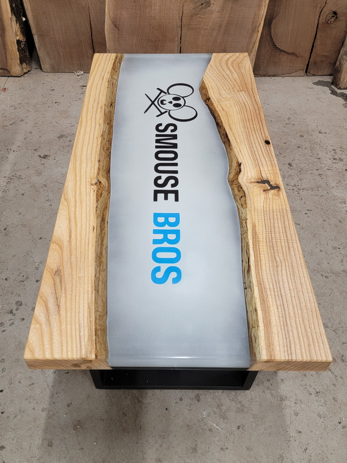 Maple table with central epoxy river with custom airbrushed company logo in black and blue that reads 'Smouse Bros' with Smouse Bros logo