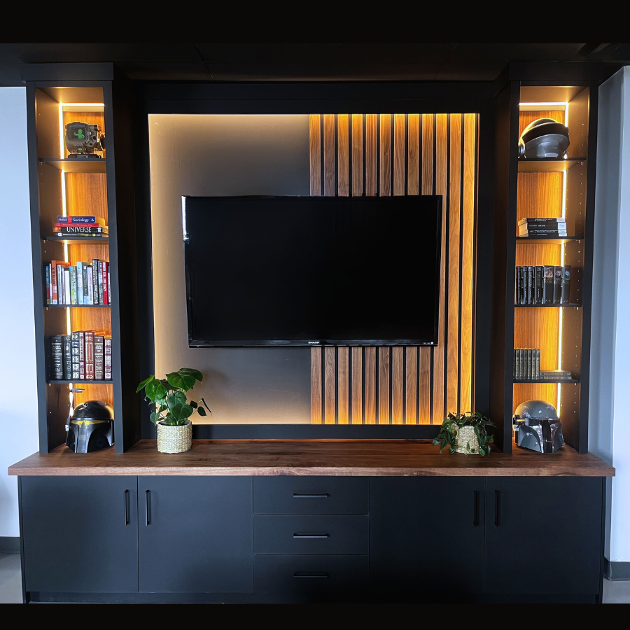 Modern entertainment center with a television and bookshelves in a room. LED-lit sections, thick walnut top, custom accent wall.