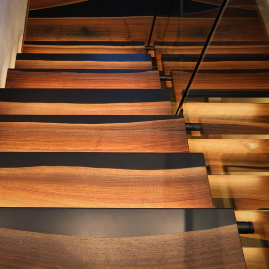 Wooden walnut staircase with black epoxy striping in a modern interior setting
