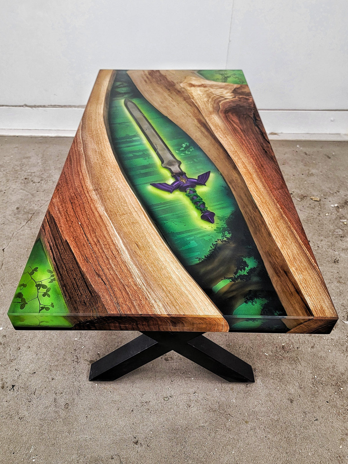 Walnut desk with epoxy central river, 3D printed Mastersword from Zelda in center. Forest green background.